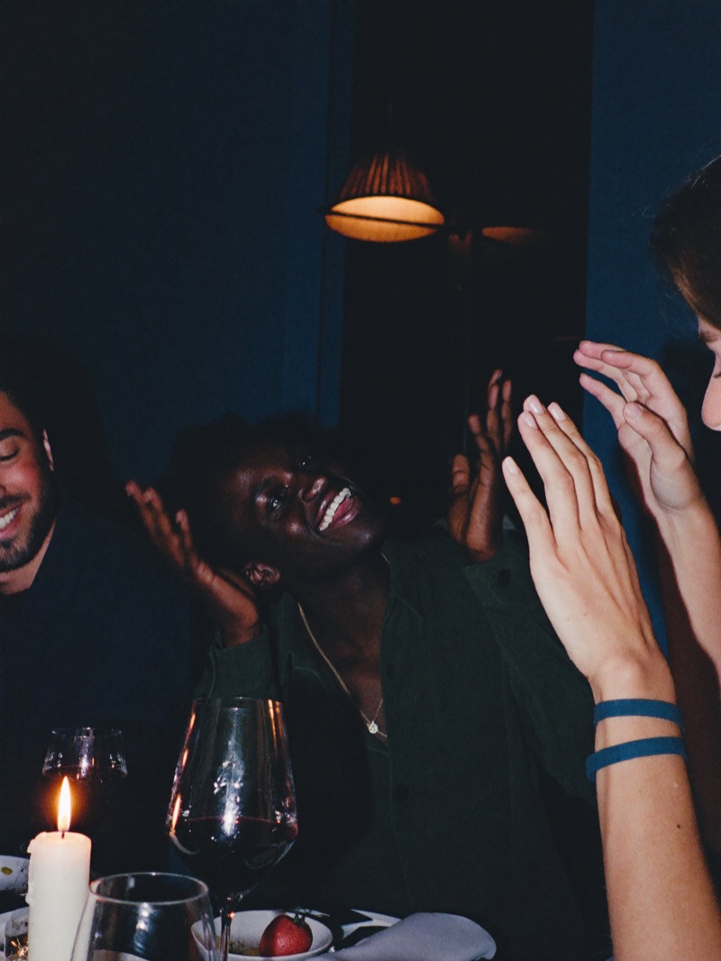 Friends laughing around a candlelit dinner table